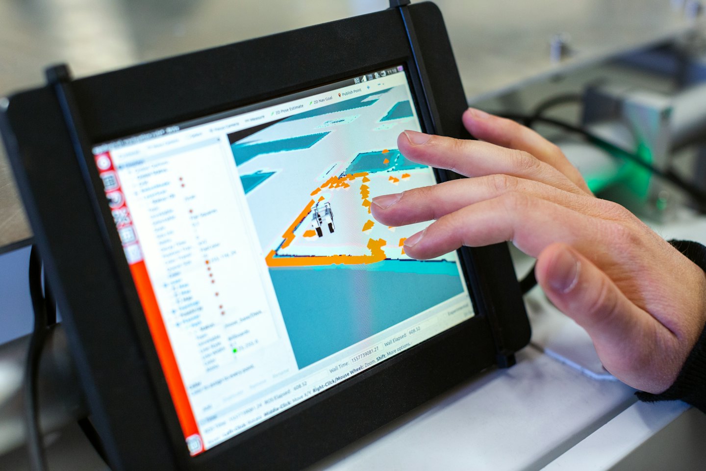Hand interacting with 3D simulation on tablet screen.