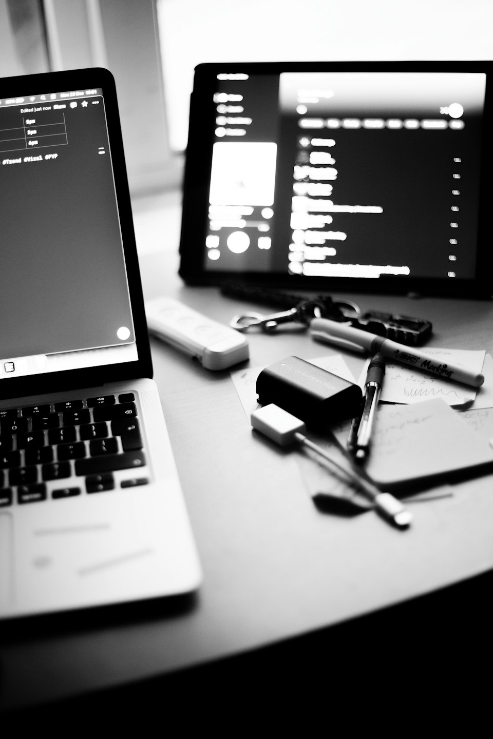 Laptop and tablet with desk accessories on a wooden desk.