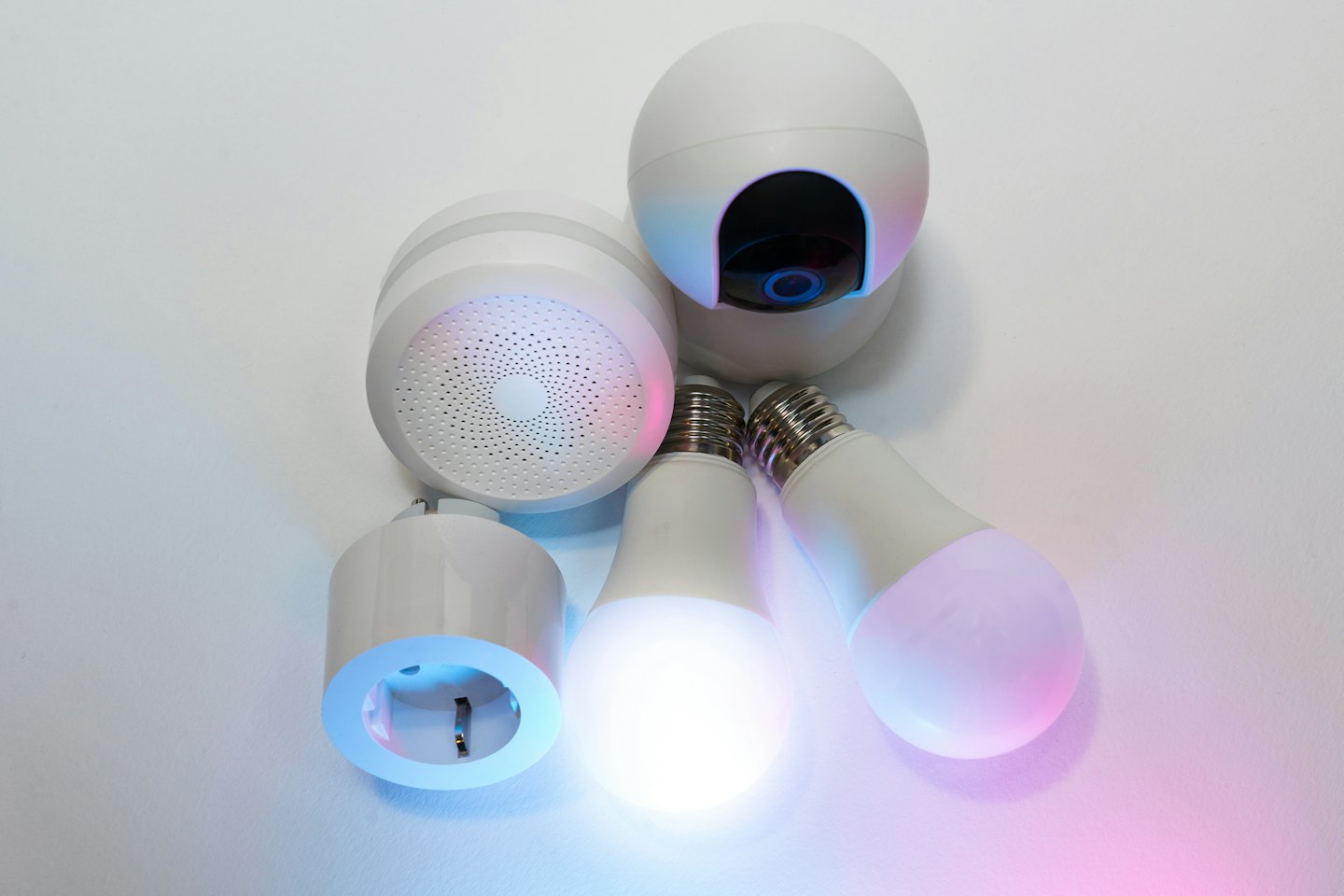 Modern smart home devices including a camera and speaker on a white surface.