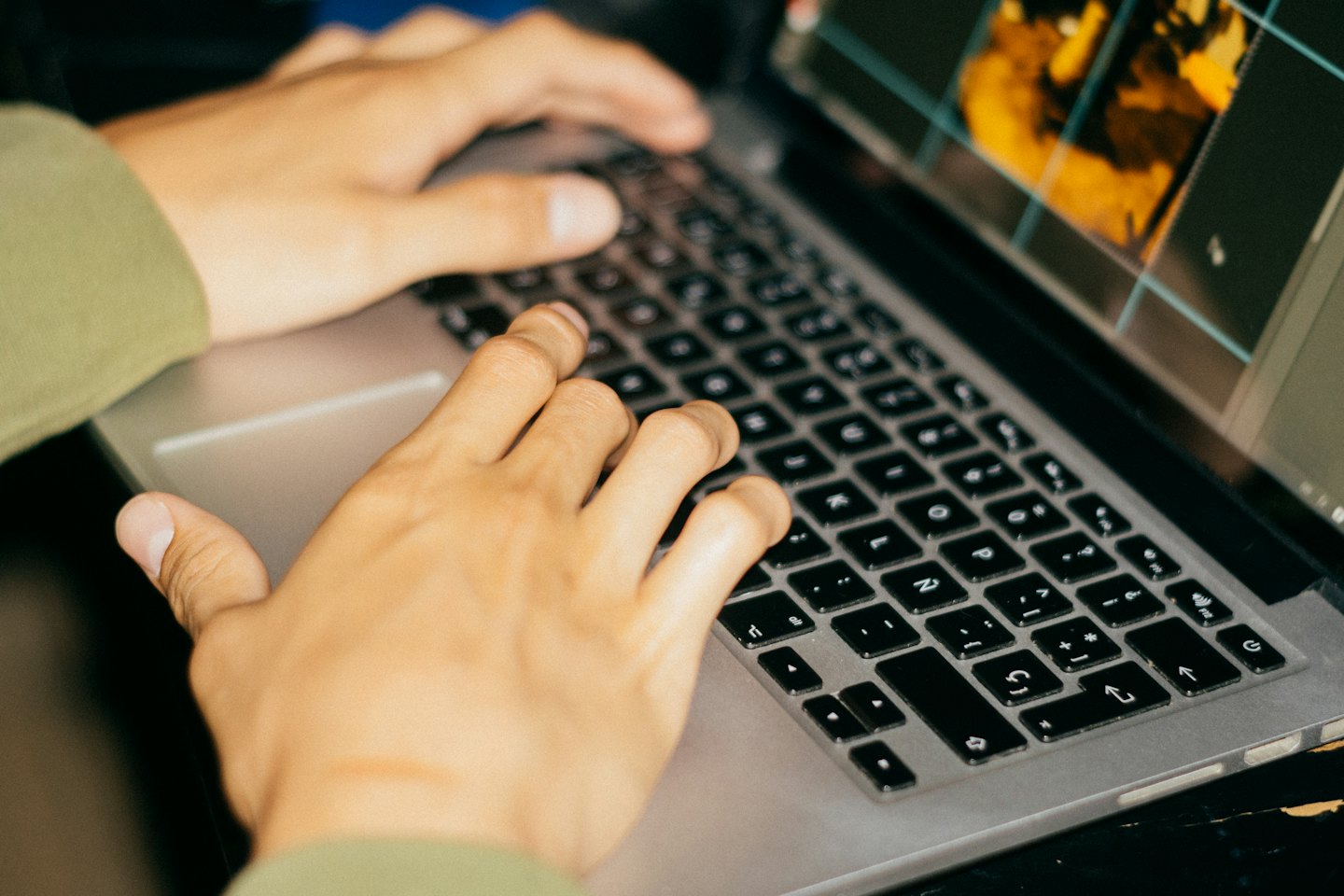 Hands typing on a laptop keyboard with an image editing interface.