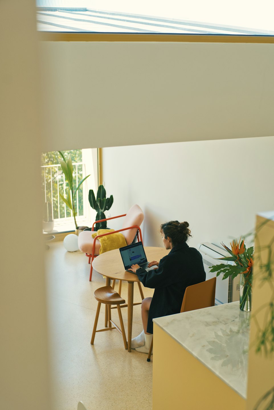 Person working on a laptop at a round wooden table.