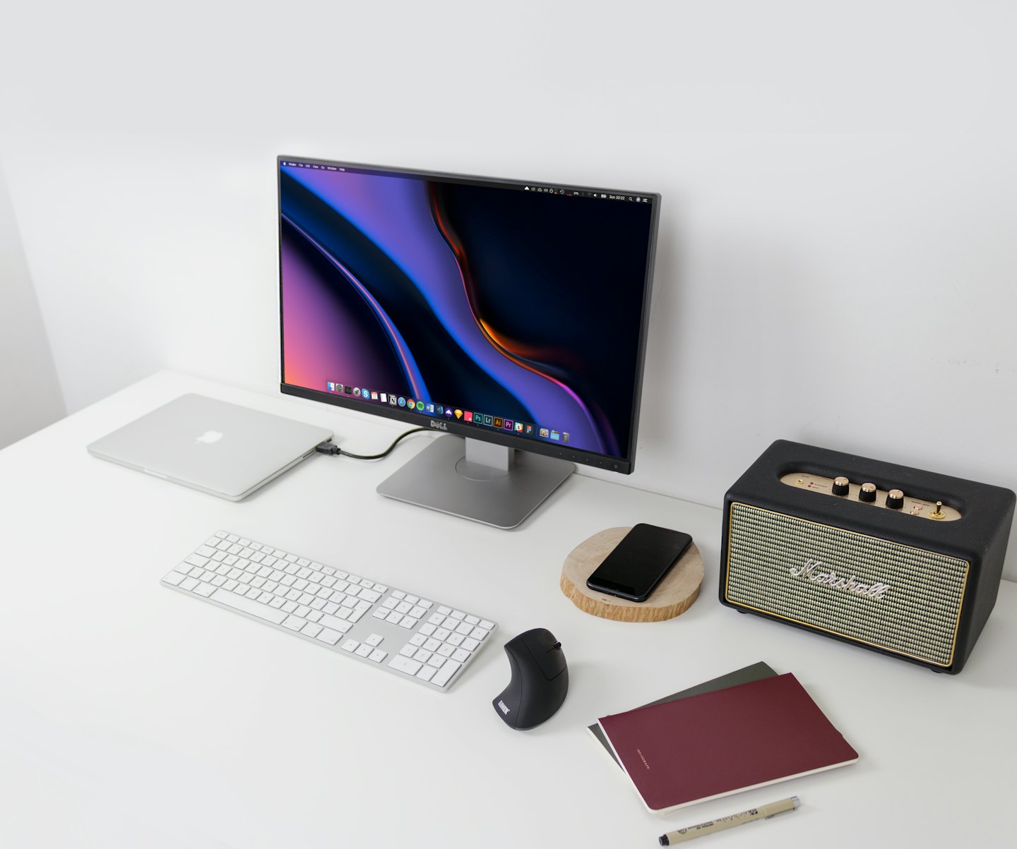 Modern desk setup with laptop, monitor, keyboard, and speaker.